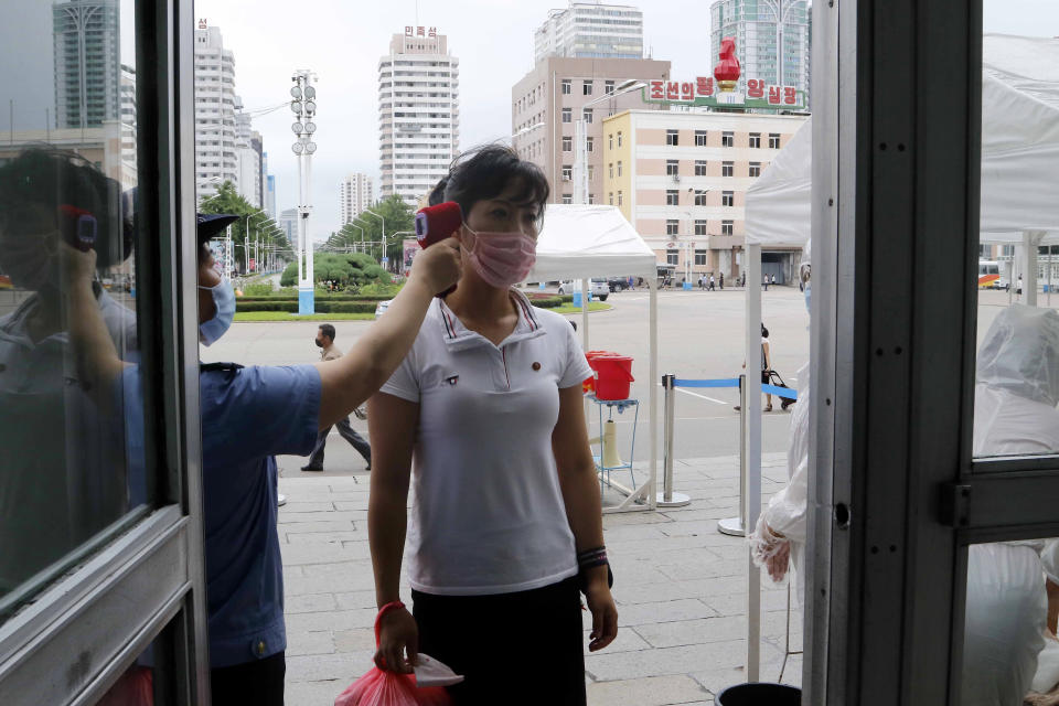 A woman wearing a face mask to help curb the spread of the coronavirus gets fever checked before going into the Pyongyang Railway Station in Pyongyang, North Korea, Thursday, Aug. 13, 2020. (AP Photo/Cha Song Ho)