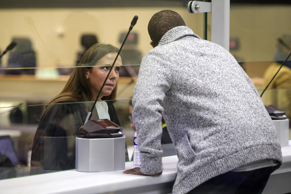 Lawyer Juliette Lurquin, left, speaks with her client through a specially designed glass box during the start of the trial for the Brussels attacks, that took place on March 22, 2016, at the Justitia building in Brussels, Monday, Dec. 5, 2022. More than six years later, ten defendants face charges including murder, attempted murder and membership, or participation in the acts of a terrorist group, over the morning rush hour attacks at Belgium's main airport and on the central commuter line on March, 22, 2016. (AP Photo/Olivier Matthys, Pool)