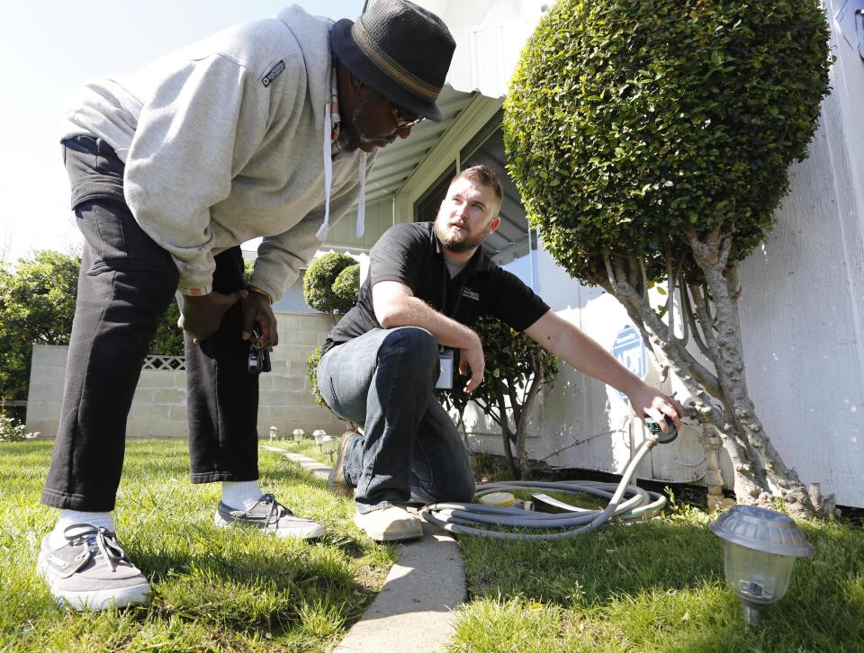 In this photo taken Tuesday, March 11, 2014, Steve Upton, right, explains to Larry Barber how to use the water timer Upton installed on the water spigot at the Barber home in Sacramento, Calif. Upton, an inspector for the water conservation unit of the Sacramento Utilities department, follows up on tips concerning city residents wasting water in one of California's driest years on record. During his visit to the Barbers, after receiving a tip they were watering their lawn on a non-watering day, Upton installed the water timer and gave them information on how to conserve water.(AP Photo/Rich Pedroncelli)