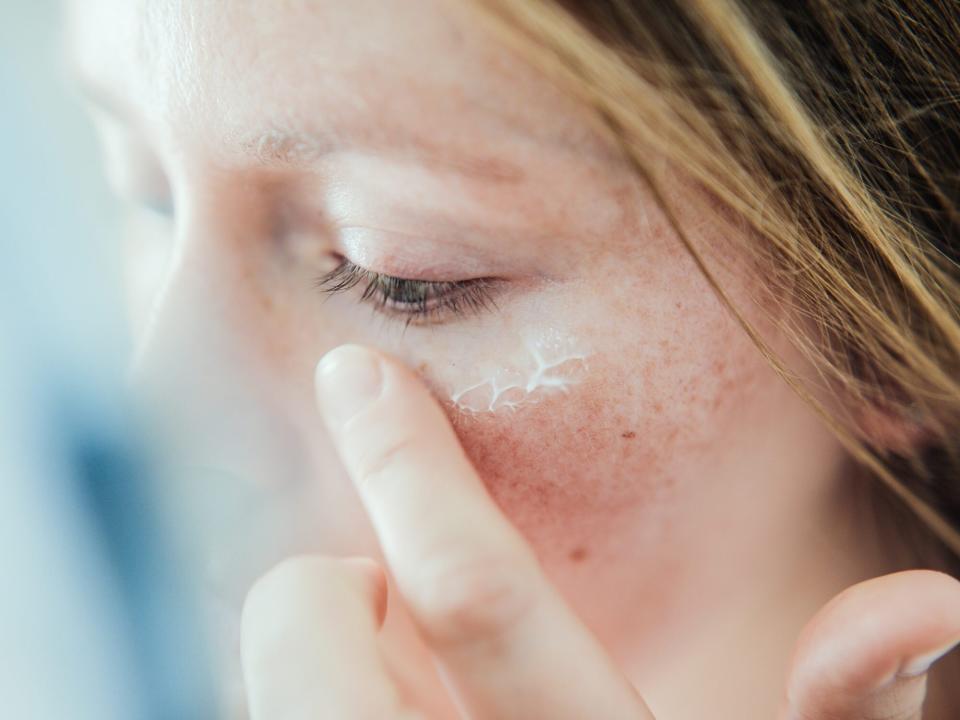 Woman applying skin face cream.