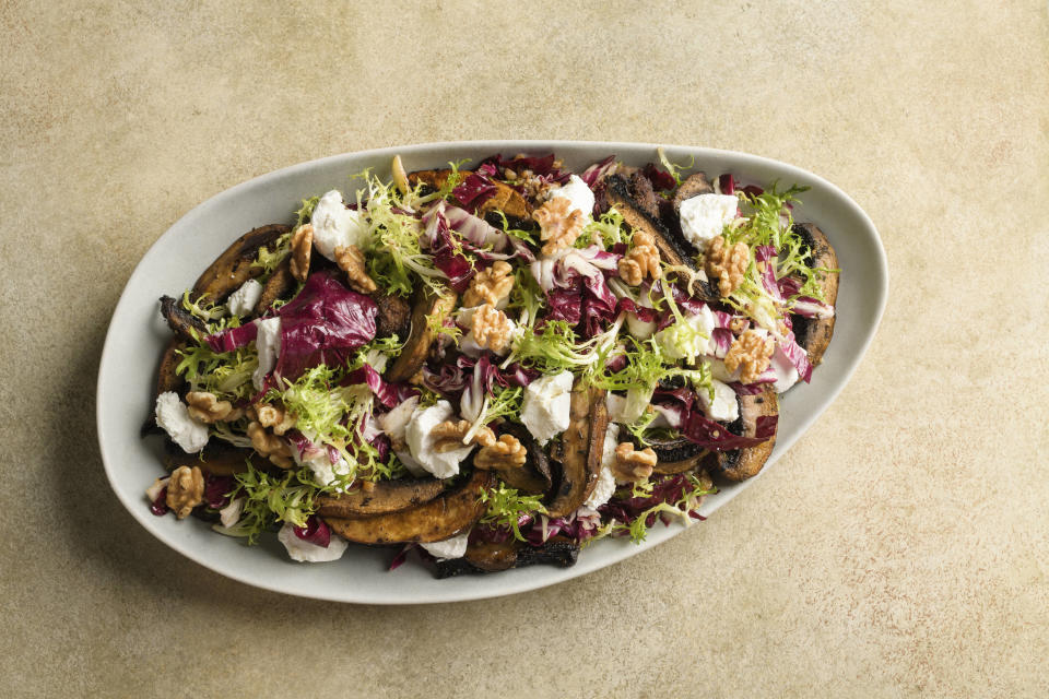 This image released by Milk Street shows a recipe for frisée and mushroom salad with goat cheese and walnuts. (Milk Street via AP)