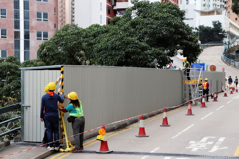 Workers erect construction hoardings around a painted slogan commemorating the 1989 Tiananmen Square crackdown, in Hong Kong