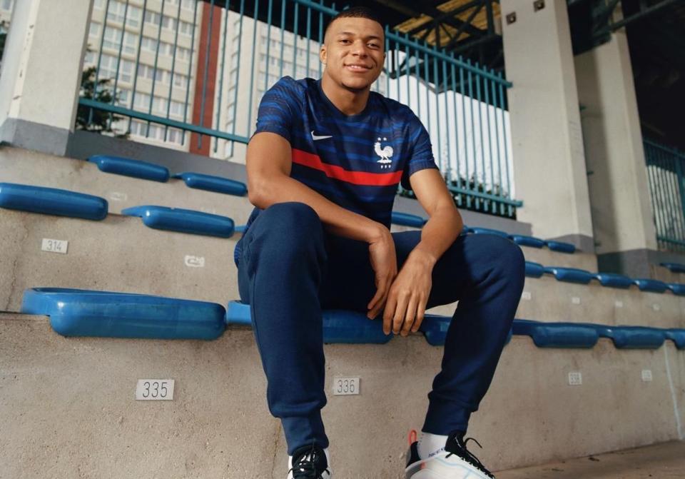 Les deux étoiles s’affichent fièrement sur le nouveau maillot de l’équipe de France. Ce mardi, Nike a dévoilé les nouveaux maillots des Bleus, qui ont retrouvé le centre d’entraînement de Clairefontaine après des mois de séparation. L’occasion pour eux d’enfiler ce nouveau maillot inspiré par les champions du monde.En clin d’oeil à l’équipe victorieuse de 1998, une large bande rouge s’étend en haut de la tenue, soulignée par une marinière discrète, bleue ton sur ton. Le coq français vient s’apposer sur le torse, sous les deux étoiles. Nike en a aussi profité pour dévoiler le kit extérieur, une tenue blanche de la tête aux pieds. Seule touche de couleur, une bande tricolore sur les côtés, sur le maillot et le short. Enfin, on découvre le maillot d’entraînement, un tee-shirt blanc agrémenté d’un motif inspiré du street-art.Pour présenter ces nouveaux maillots, Nike a fait appel à son égérie, la star des Bleus et du Paris Saint Germain, Kylian Mbappé, qui déclare : « Je pense qu’il y a deux ans, nous avons uni le pays, tout comme en 1998. Maintenant, nous allons porter une bande rouge sur notre maillot, comme ils l’ont fait. C’était une grande équipe, qui a créé un héritage. Il est temps pour nous de continuer à nous efforcer d’être les meilleurs et de créer le nôtre. »Le nouveau maillot des Bleus sera visible pour la première le 5 septembre, lors du match qui opposera les Bleus à la Suède, dans le cadre de la Ligue des Nations, à Stockholm. L’équipe de France fera ensuite son retour au Stade de France le 8 septembre contre la Croatie, équipe qu’elle avait vaincue en finale de Coupe du monde, à Moscou, en 2018.