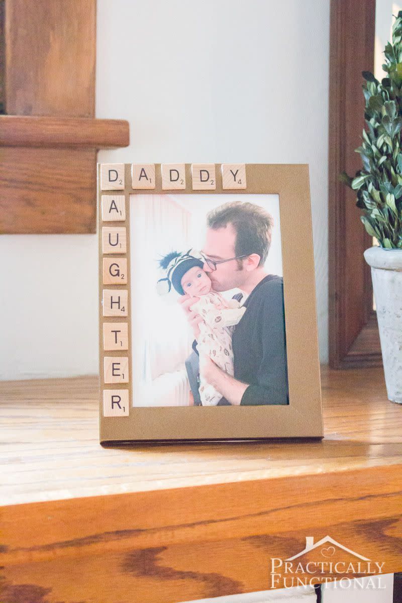 father's day crafts, picture of a father holding his baby framed in a picture frame decorated with scrabble letters