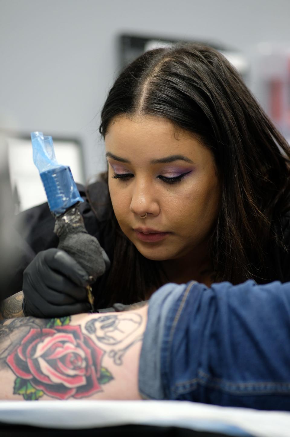 Elva Stephanie from Inkmaster gives a tattoo during All American Tattoo Society's Dec. 19, 2023, grand opening on Fort Liberty.