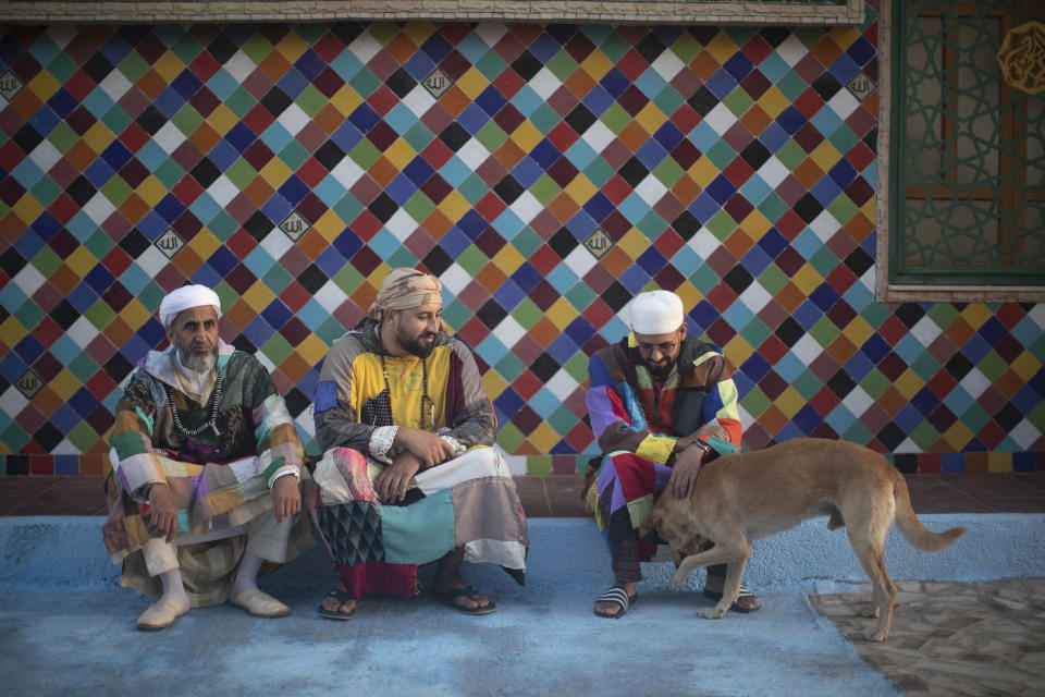 Members of the Sufi Karkariya order pet a dog as they gather during a religious celebration of the birthday of the prophet Muhammed, in Aroui, near Nador, eastern Morocco, Monday, Oct. 18, 2021. (AP Photo/Mosa'ab Elshamy)