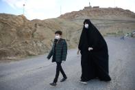 A woman and her son wearing protective face masks and gloves, following the outbreak of coronavirus disease (COVID-19), walk in the highlands in Qom