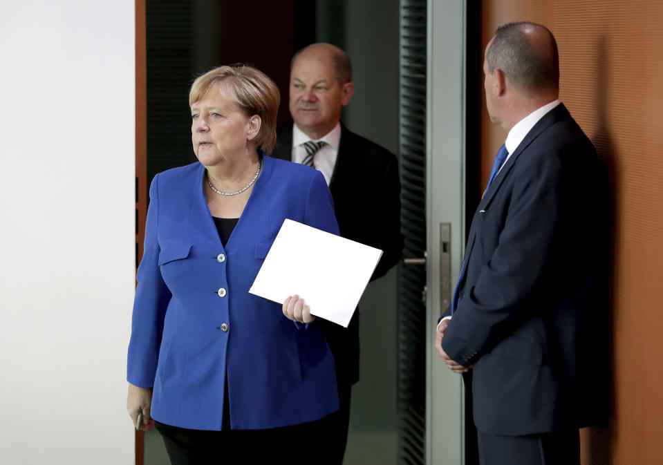 German Chancellor Angela Merkel, left, and German Finance Minister Olaf Scholz, center, arrive for the weekly cabinet meeting at the Chancellery in Berlin, Germany, Wednesday, Oct. 23, 2019. (AP Photo/Michael Sohn)