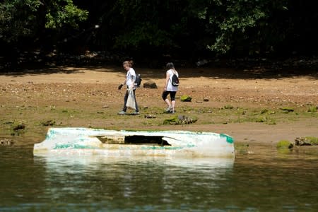 Volunteers walk past a sunken plastic boat during in the Zero Plastiko Urdaibai ocean and coastal cleanup near Bermeo