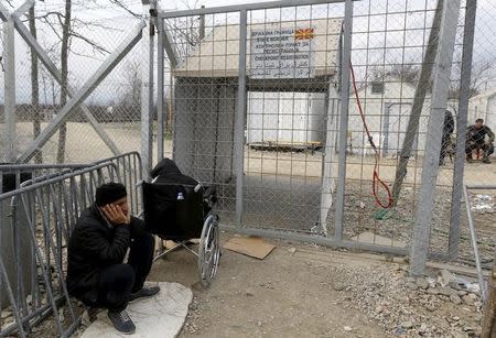 Stranded wheelchair-bound Zhino Hasan, 17, and her father Sarkawt wait in front of a closed border gate at Idomeni, hoping that Macedonia would relent and allow her and her family to resume their northward trek through the Balkans to Germany, February 26, 2016. REUTERS/Yannis Behrakis