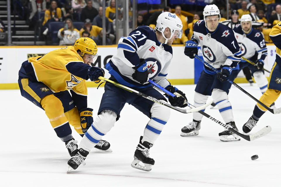 Nashville Predators defenseman Jeremy Lauzon (3) reaches in as Winnipeg Jets left wing Nikolaj Ehlers (27) gets control of the puck during the first period of an NHL hockey game Saturday, March 18, 2023, in Nashville, Tenn. (AP Photo/Mark Zaleski)
