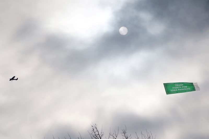 A plane towing a campaign ad for President Trump flies over the site of the seventh Democratic 2020 presidential debate in Des Moines