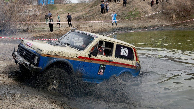 A photo of an off-road car driving through mud. 