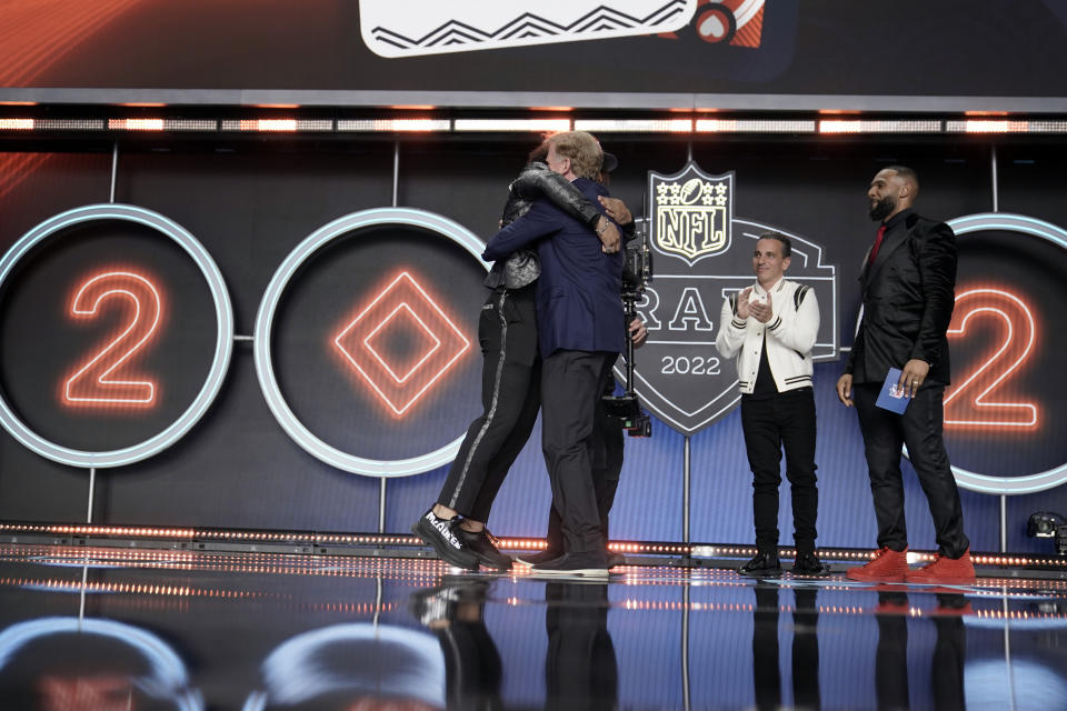 Washington cornerback Kyler Gordon, left,, hugs NFL Commissioner Roger Goodell, second from left, as former Chicago Bears running back Matt Forte, right, and comedian Sean Sebastian Maniscalco, second from right, look on after being selected by the Bears during the second round of the NFL football draft Friday, April 29, 2022, in Las Vegas. (AP Photo/Jae C. Hong)