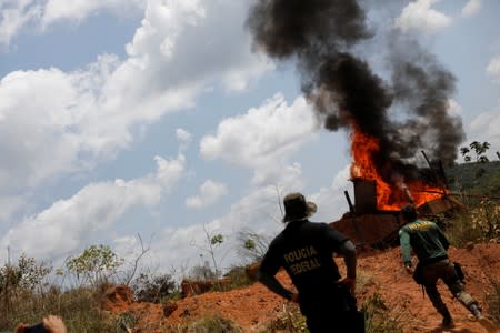 An agent of IBAMA and a Police Federal officer look on as machines are destroyed during an operation conducted at an illegal gold mine near the city of Altamira