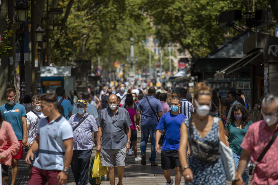 People walk along the Ramblas of Barcelona, Spain, Thursday, July 16, 2020. With Europe's summer vacation season kicking into high gear for millions weary of months of lockdown, scenes of drunken British and German tourists on Spain's Mallorca island ignoring social distancing rules and reports of American visitors flouting quarantine measures in Ireland are raising fears of a resurgence of infections in countries that have battled for months to flatten the COVID-19 curve. (AP Photo/Emilio Morenatti)