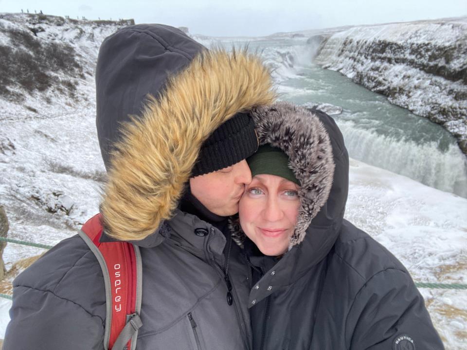 Couple dressed in winter clothes hugging with snow background