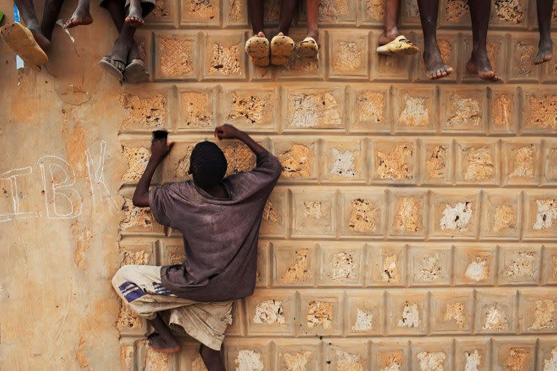 FILE PHOTO: A boy climbs a wall to watch a campaign rally for presidential candidate Ibrahim Boubacar Keita in Timbuktu