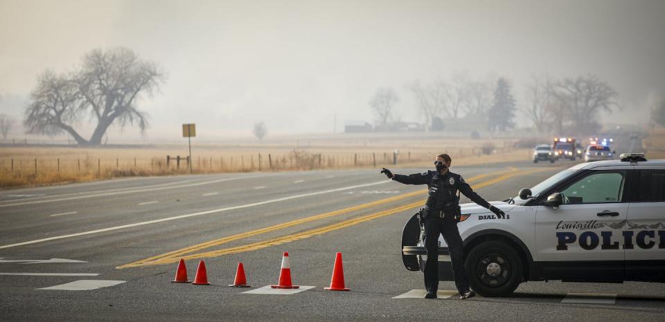 A police officer directs traffic away from a closed road as fast-moving wildfires force evacuations on Dec. 30, 2021, in Louisville, Colorado. <a href="https://www.gettyimages.com/detail/news-photo/louisville-police-officer-directs-traffic-away-from-a-news-photo/1237478100" rel="nofollow noopener" target="_blank" data-ylk="slk:Marc Piscotty/Getty Images;elm:context_link;itc:0;sec:content-canvas" class="link ">Marc Piscotty/Getty Images</a>