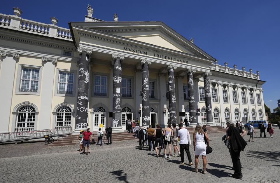 Visitors cue in front of the museum Fridericianum during the press preview of the documenta 15, the world's most significant exhibition of contemporary art, in Kassel, Germany, Wednesday, June 15, 2022. This years documentary is curated by Indonesian artist collective Ruangrupa, every documenta is limited to 100 days of exhibition and takes place every 5 years. (AP Photo/Martin Meissner)