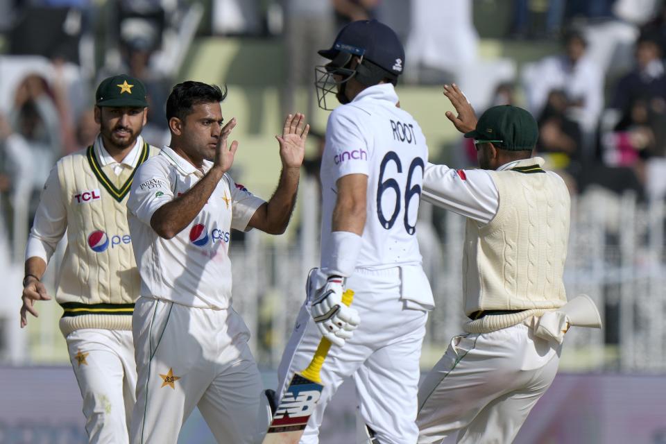 Pakistan's Zahid Mahmood, second left, celebrates with teammates after taking the wicket of England's Joe Root, second right, during the first day of the first test cricket match between Pakistan and England, in Rawalpindi, Pakistan, Dec. 1, 2022. (AP Photo/Anjum Naveed)