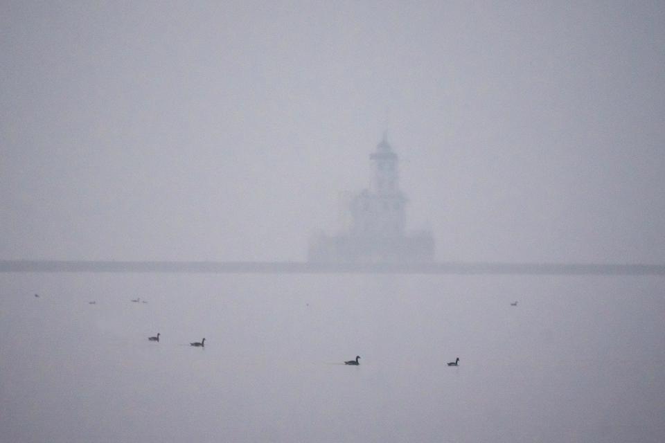 The Breakwater lighthouse is obscured as smoke from the Canadian wildfires continues to linger in the air in Milwaukee on Friday morning.