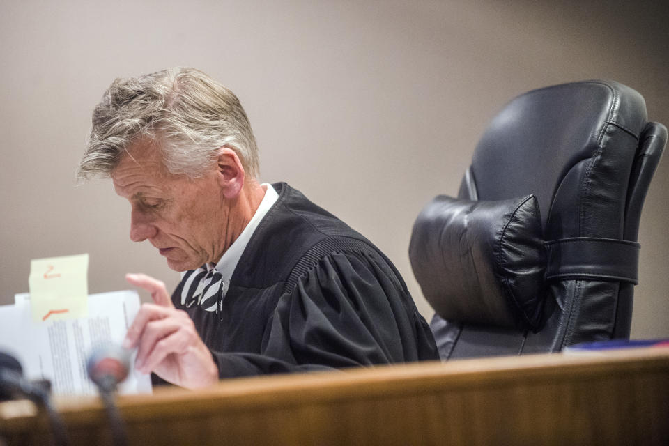 Genesee District Judge David J. Goggins examines the case as he gives his decision during the preliminary examination of Nick Lyon on Monday, Aug. 20, 2018 at Genesee District Court in Flint, Mich. Goggins ordered Lyons to stand trial for involuntary manslaughter in two deaths linked to Legionnaires' disease in the Flint area, the highest ranking official to stand trial as a result of the tainted water scandal. (Jake May/The Flint Journal via AP)