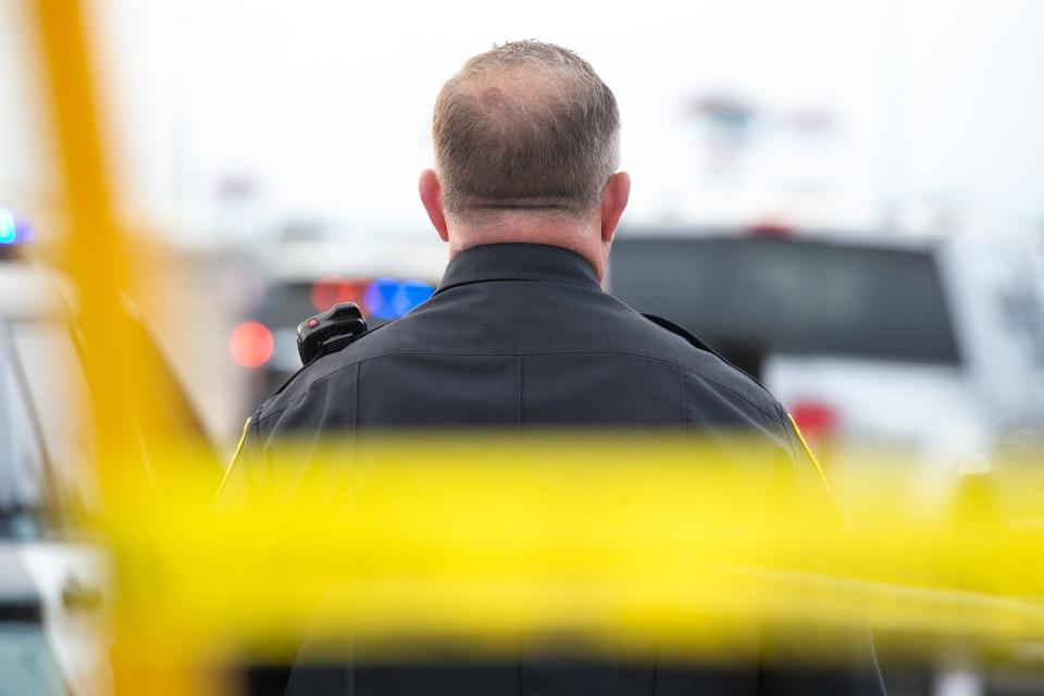 A Corpus Christi police officer stands behind police tape at a crime scene on South Padre Island Drive Saturday, Dec. 3, 2022.