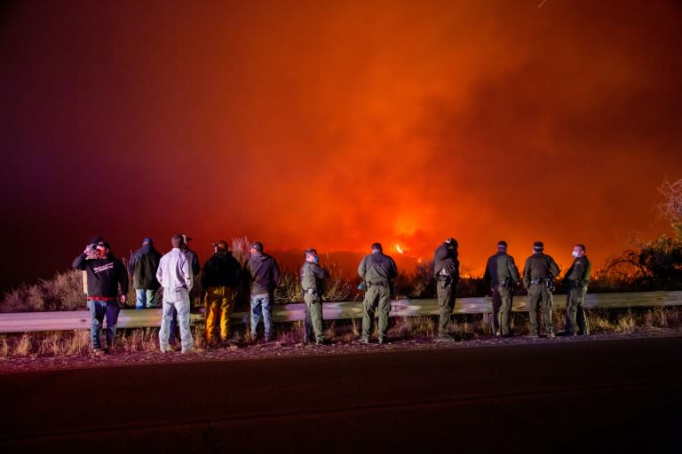 Police and fire crews watch as the "Thomas Fire" burns a hillside in Ojai, California