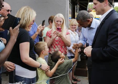 U.S. President Barack Obama shakes hands with a child as he walks along Grand Ave. in St. Paul, Minnesota, June 26, 2014. REUTERS/Larry Downing