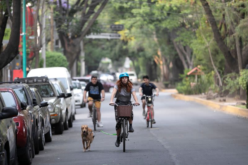 A woman rides a bicycle while walking her dog after Mexico's government declared a health emergency on Monday and issued stricter rules aimed at containing the fast-spreading coronavirus disease (COVID-19), in Mexico City