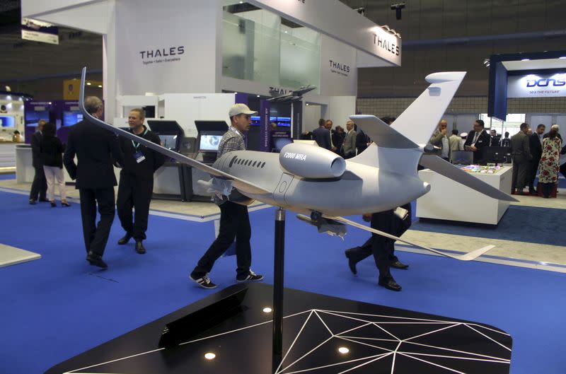 FILE PHOTO: Visitors walk next to model of Dassault Falcon 2000 MRA aircraft during Doha International Maritime Defence Exhibition