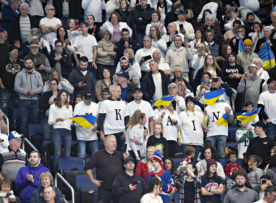 Spectators dressed in white cheer for the Ukraine peewee team cheer during a hockey game against the Boston Junior Bruins, Saturday, Feb. 11, 2023 in Quebec City. (Jacques Boissinot/The Canadian Press via AP)