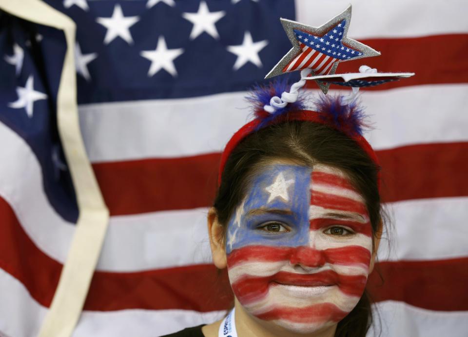 A fan with her face painted in the colours of the U.S. flag, is seen in front of the U.S. flag as she attends the women's preliminary round hockey game between Team USA and Switzerland at the Sochi 2014 Winter Olympic Games