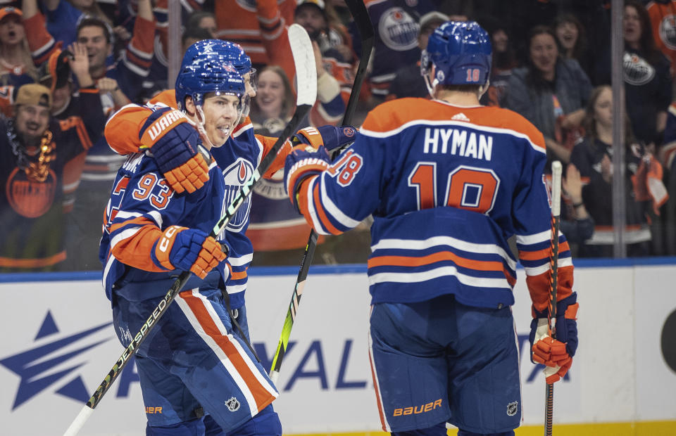 Edmonton Oilers' Ryan Nugent-Hopkins (93), Leon Draisaitl (29) and Zach Hyman (18) celebrate a goal against the Vancouver Canucks during the second period of an NHL hockey game in Edmonton, Alberta, Saturday, Oct. 14, 2023. (Jason Franson/The Canadian Press via AP)