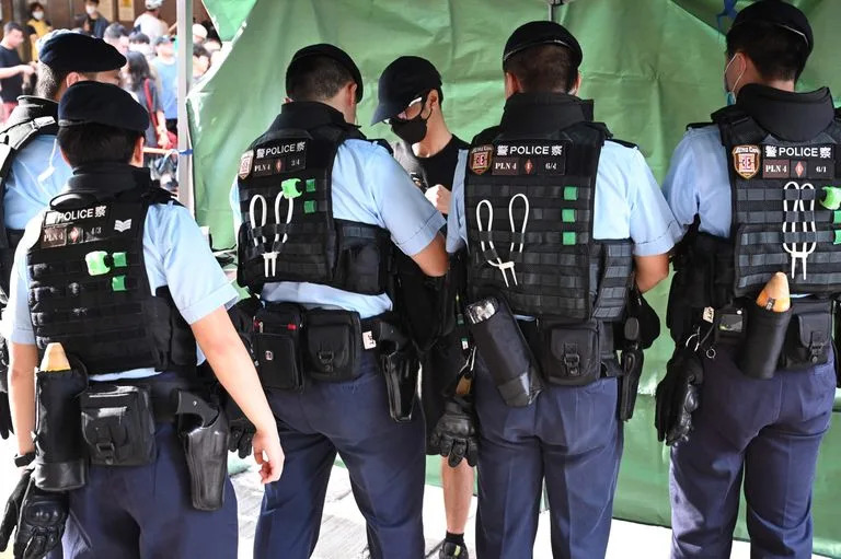 La polic&#xed;a interroga a un hombre en el distrito comercial de Causeway Bay de Hong Kong el 4 de junio de 2023, cerca del lugar donde los hongkoneses se re&#xfa;nen tradicionalmente cada a&#xf1;o para llorar a las v&#xed;ctimas de la represi&#xf3;n china de la plaza de Tiananmen en 1989, que las autoridades han prohibido y prometido acabar con cualquier protesta en el aniversario del 4 de junio.