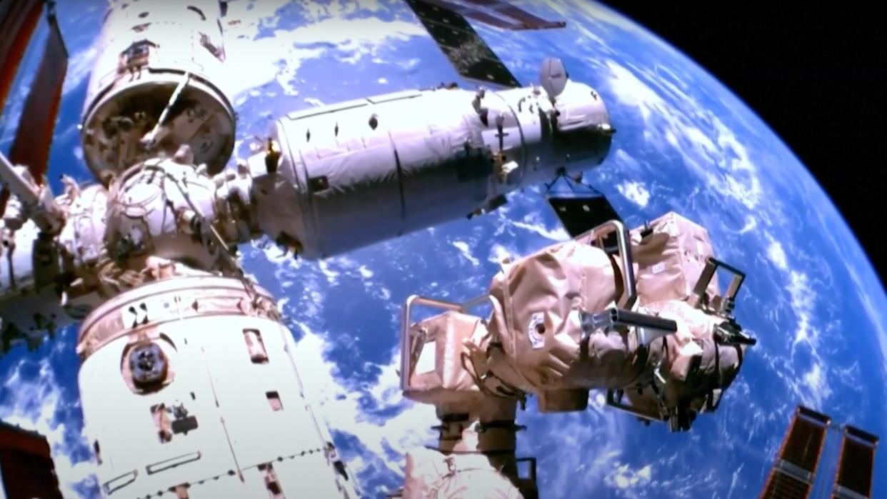  A three-module space station seen up close, with earth in the background. 