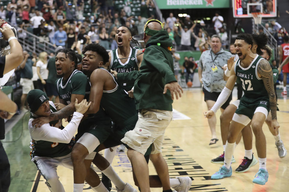 Hawaii guard JoVon McClanahan, second from left, jumps into the crowd with teammates after making a 3-point shot to put Hawaii ahead of SMU at the end of an NCAA college basketball game, Sunday Dec. 25, 2022, in Honolulu. Hawaii defeated SMU 58-57 to win the Diamond Head Classic tournament. (AP Photo/Marco Garcia)