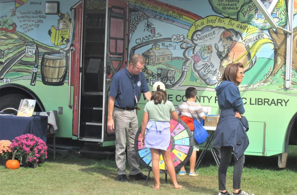 Jeff Kilgore helps visitors spin the wheel for a chance to win free book from the Wayne County Public Library. The library Summer Reading Program for youth and adults begins Tuesday. (DAILY RECORD FILE PHOTO)