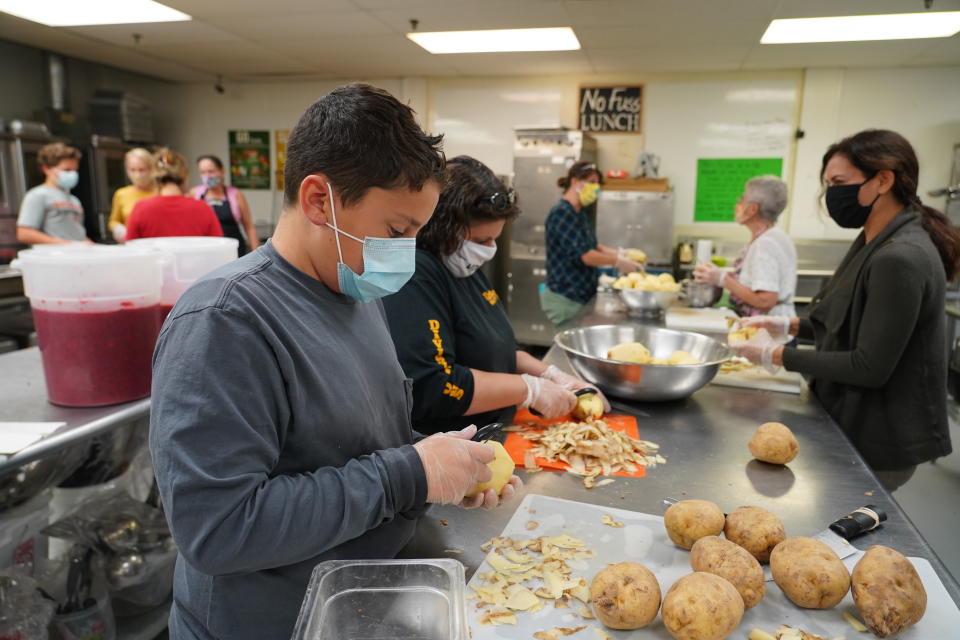 Volunteers peel potatoes and prepare other Thanksgiving food for seniors in Hawthorne, N.J., on Nov. 3, 2020.. With a fall surge of coronavirus infections gripping the U.S., many Americans are forgoing tradition and getting creative with celebrations. (AP Photo/Kathy Young)