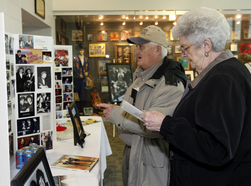Everly Brothers fans Garnett, left, and Elizabeth Rhoades, right, of Central City, Ky, look over photos an memorabilia of the Everly Brothers before a memorial service to Phil Everly at the Merle Travis Music Center in Powderly, Ky, Saturday, Jan. 18, 2014. (AP Photo/John Sommers II)