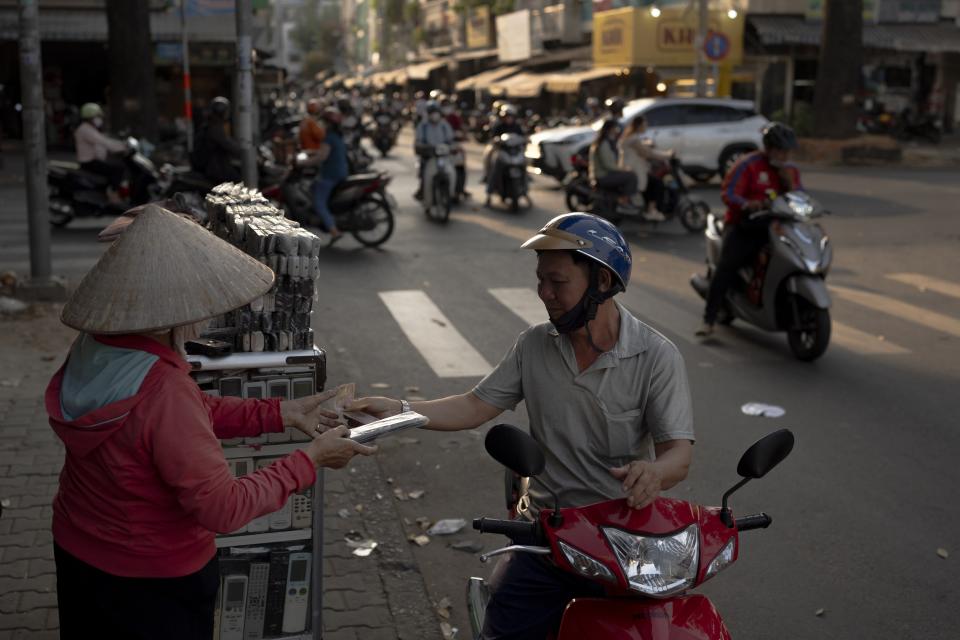 A man sitting on a scooter purchases a used remote control for a home appliance from a vendor in Nhat Tao market, the largest informal recycling market in Ho Chi Minh City, Vietnam, Wednesday, Jan. 31, 2024. The world is producing more electronic waste than ever. And it's growing faster than formal efforts to recycle it. (AP Photo/Jae C. Hong)