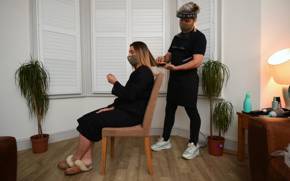 Secret Spa hair stylist Nas Ganev finishes styling the hair of Amy Pallister, 27, at the end of her appointment which began just after midnight at her home in Balham, south London - PA