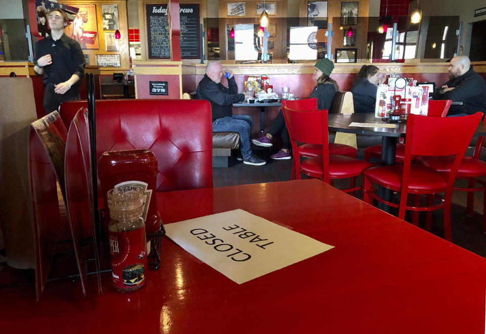 FILE - In this March 15, 2020, file photo, a Red Robin restaurant in Tigard, Ore., has closed some tables in order to maintain social distancing between diners per CDC guidelines. Oregon Gov. Kate Brown on Friday, Nov. 13, 2020, announced a statewide two-week "freeze" which will limit restaurants and bars to take-out only and close gyms, indoor and outdoor recreational facilities during that period. If people do not abide by the governor's latest mandates, which restricts social gatherings to six people, they could face a citation, fine or arrest. (AP Photo/Gillian Flaccus, File)