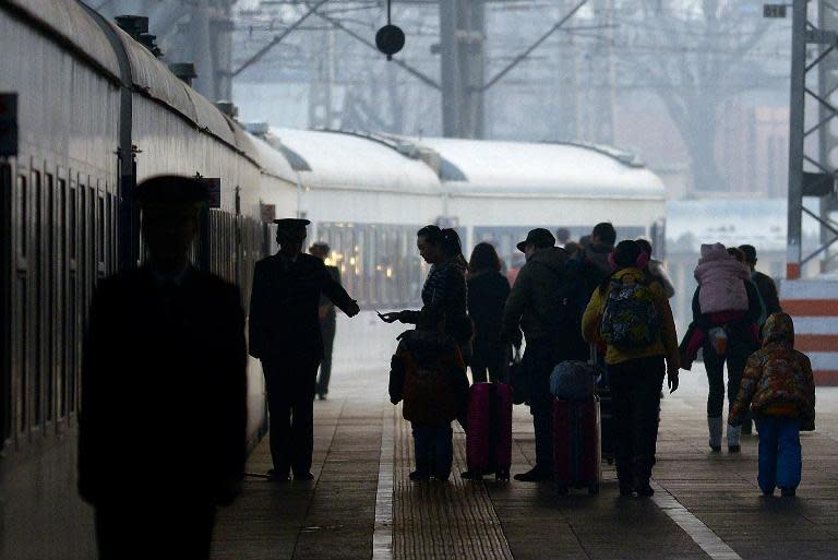Travellers prepare to board a train at a railway station in Beijing, on January 23, 2014, during the world's largest annual migration, with tens of thousands journeying home for Lunar New Year celebrations