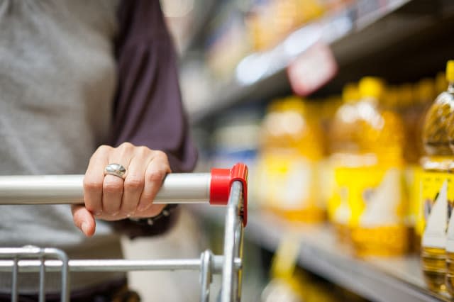 Woman hand close up with shopping cart in a supermarket walking trough the aisle.