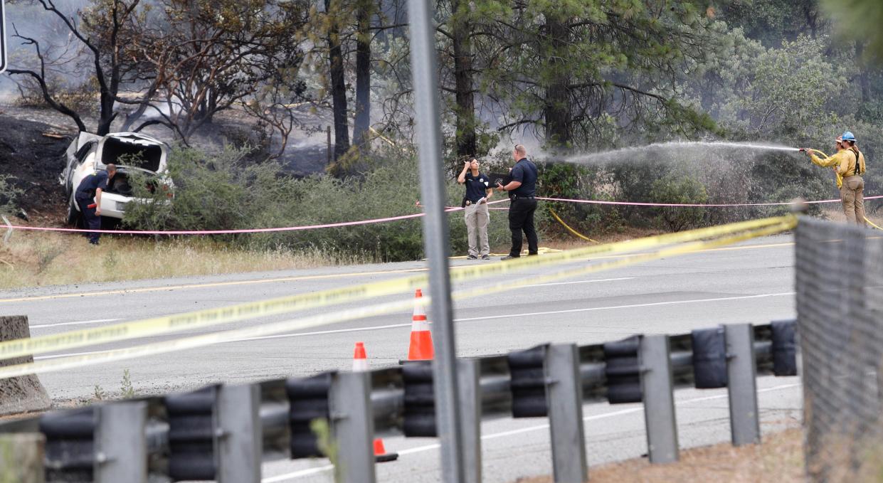 A firefighter sprays water on a smoldering hillside where a car crashed along northbound Interstate 5 on Thursday afternoon, May 26, 2022, and where there was an officer-involved shooting. The shooting took place near the O'Brien rest area and shut down northbound I-5 for hours.
