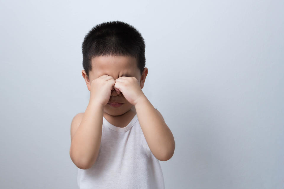 Portrait of exhausted and tired asian boy rubbing his eyes.