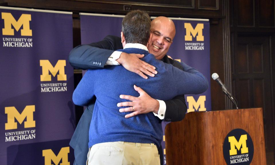 Michigan's new athletic director Warde Manuel gets a hug from football coach Jim Harbaugh before Harbaugh presented him with a football jersey during a news conference, Friday, Jan. 29, 2016, at the Student Union in Ann Arbor, Mich.  The 47-year-old Manuel, who had been Connecticut's athletic director since 2012, was given a five-year deal by Michigan. The salary was not immediately disclosed. (Dale G. Young/Detroit News via AP)  DETROIT FREE PRESS OUT; HUFFINGTON POST OUT; MANDATORY CREDIT