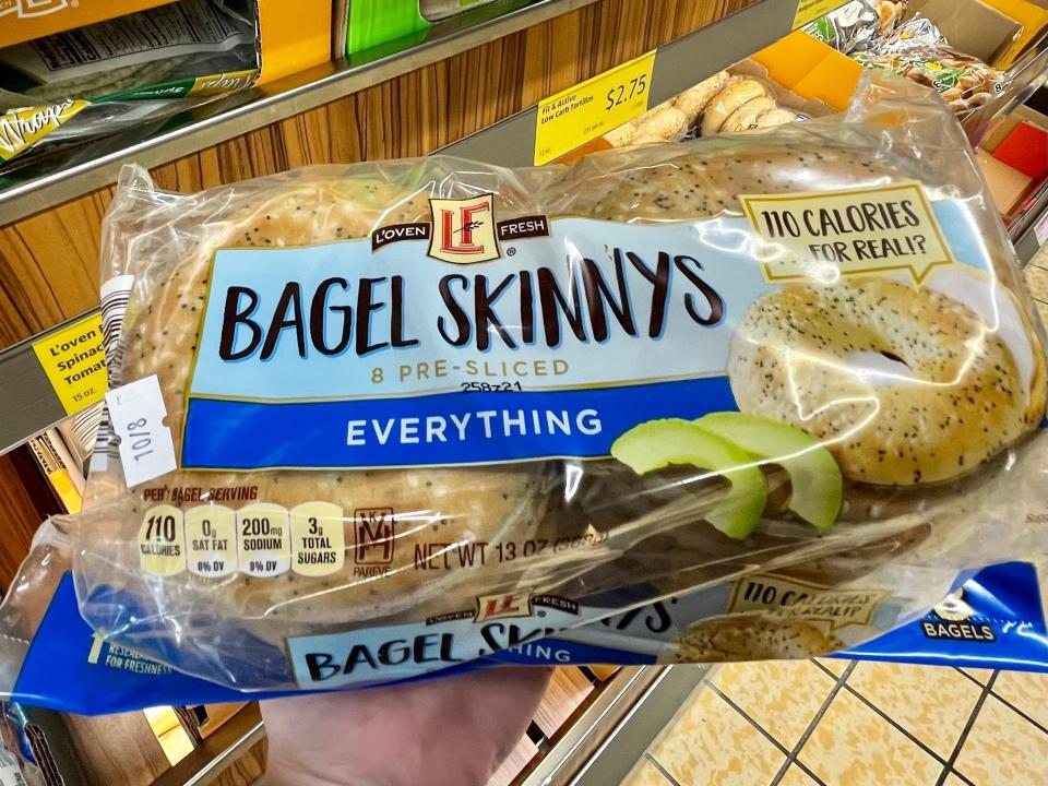 Hand holding blue and clear package of Aldi bagel things